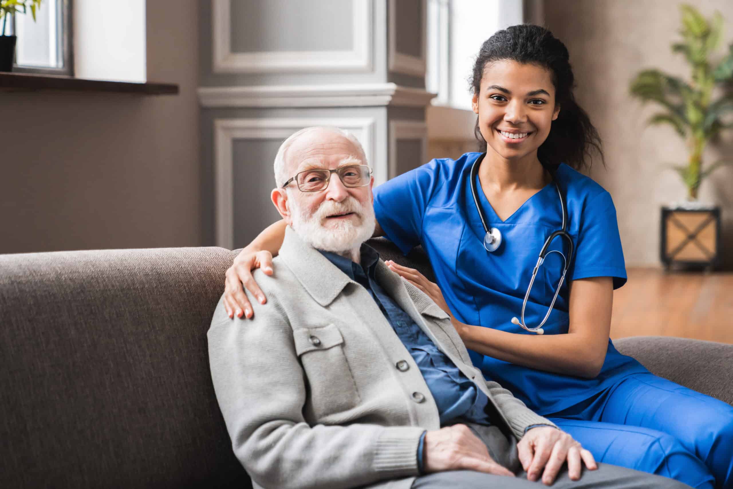 Front view portrait of caring afro nurse taking care of an elderly caucasian man grandfather grandpa indoors Happy female doctor consulting old man in clinic